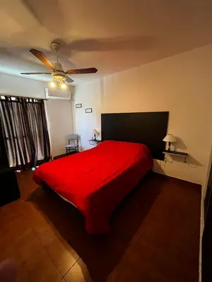 a bedroom with a red bed and a ceiling fan at Departamento Santa rita in Villa Carlos Paz