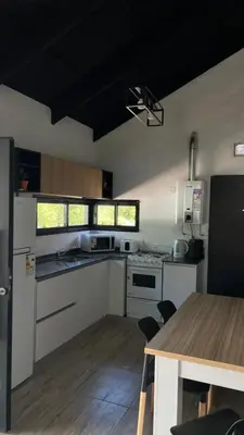 a kitchen with white appliances and a wooden table at Altos de Lagunitas in Villa General Belgrano