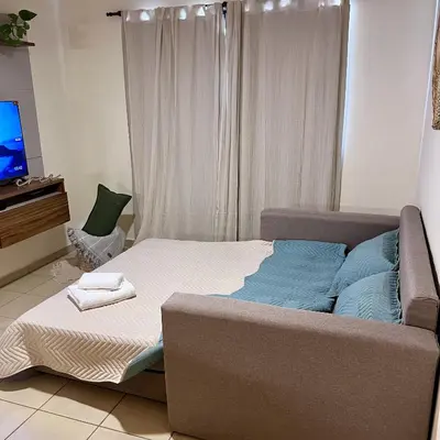 a bedroom with a bed and a couch and a television at Departamento céntrico con cochera Muy cómodo cerca de todo in Villa Carlos Paz