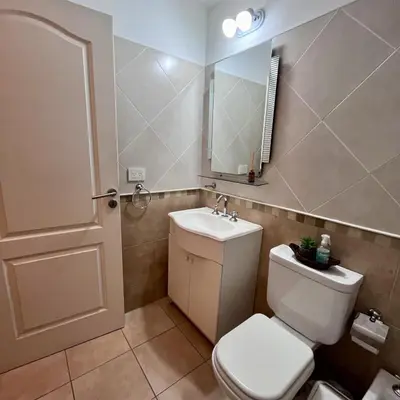 a bathroom with a toilet and a sink and a mirror at Departamento céntrico con cochera Muy cómodo cerca de todo in Villa Carlos Paz