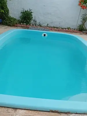 a blue pool in front of a house at La Casita del tano con Pileta in Villa Carlos Paz