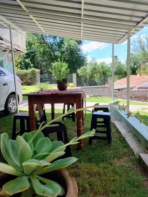 a table and chairs under a pavilion with a potted plant at La casa del Algarrobo in San Antonio de Arredondo