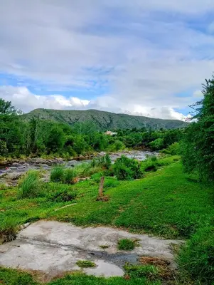 a river in a field with mountains in the background at La casa del Algarrobo in San Antonio de Arredondo