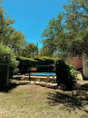 a swimming pool in a yard with a fence and trees at La Herradura in Mina Clavero