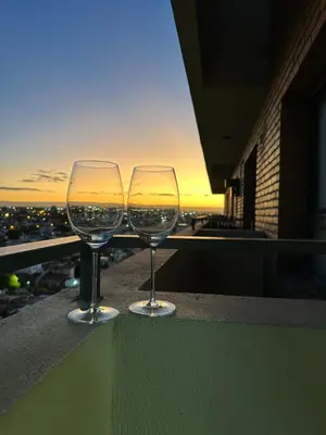two wine glasses sitting on a ledge overlooking a city at Departamento premium con balcón, vista y atardeceres in Cordoba