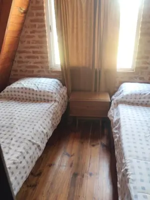 two beds in a room with wooden floors and windows at Altos del torreón in Villa Rumipal