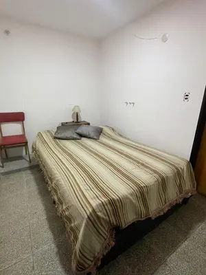 a large bed in a room with a red chair at casita Playas de oro in Villa Carlos Paz