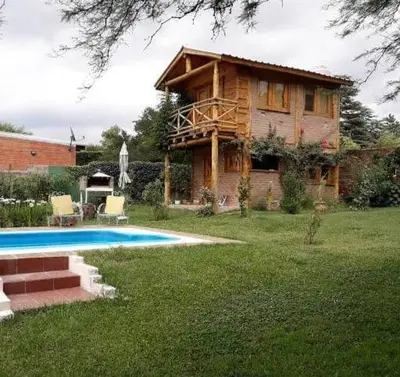 a log house with a swimming pool in the yard at Cabañas L' armonie in Bialet Massé