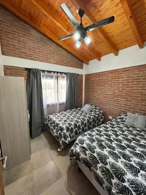 a bedroom with two beds and a ceiling fan at Cabaña Valle del alma in Nono