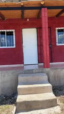 a red building with a white door and some stairs at Dulce Azul in Villa García