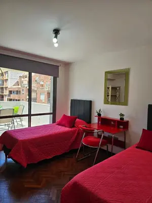 a bedroom with two beds and a table and a mirror at Moderno departamento con terraza privada in Cordoba