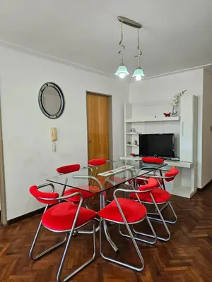 a dining room with a glass table and red chairs at Moderno departamento con terraza privada in Cordoba
