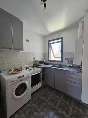 a kitchen with a stove and a washing machine at Moderno departamento con terraza privada in Cordoba