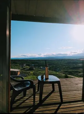 a table and a chair on a balcony with a view at Cabañas La Puesta del Sol in Estancia Vieja