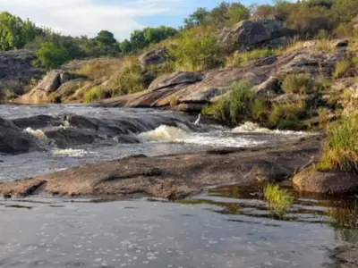 a river with rapids on the side of a hill at Cabañas La Puesta del Sol in Estancia Vieja