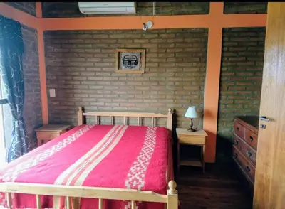 a bedroom with a bed and a brick wall at Cabañas La Puesta del Sol in Estancia Vieja
