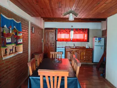 a kitchen with a table with chairs and a refrigerator at Cabañas La Puesta del Sol in Estancia Vieja