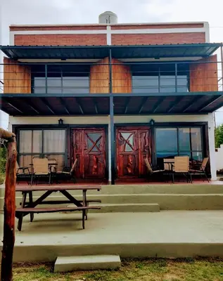 a house with red doors and a picnic table in front of it at Cabañas La Puesta del Sol in Estancia Vieja