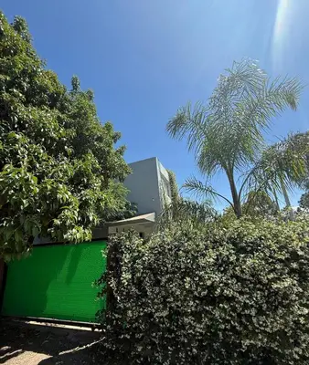 a green wall in front of a building with trees at La casa accesible y perfecta para tus vacaciones in Villa Santa Cruz del Lago