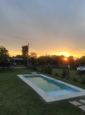 a swimming pool in a yard with the sunset in the background at Sol y Calma in Villa Rumipal