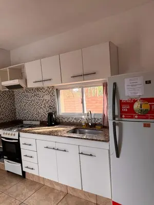 a kitchen with white cabinets and a sink and a refrigerator at Complejo EbenEzer in Merlo