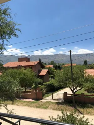 a village with a fence and a building and mountains at Complejo EbenEzer in Merlo