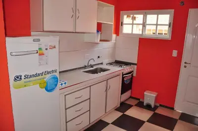 a small kitchen with a white refrigerator and red walls at Complejo Carola in Villa Carlos Paz