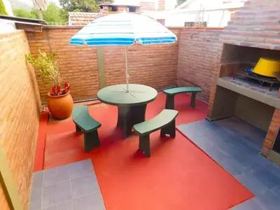 a patio with a table and benches and an umbrella at Complejo Carola in Villa Carlos Paz