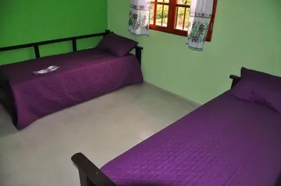 two beds in a room with purple sheets at Complejo Carola in Villa Carlos Paz
