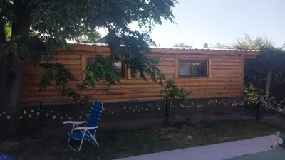 a blue chair in front of a log cabin at Exclusiva cabaña in Villa Santa Cruz del Lago