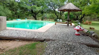 a small swimming pool with a umbrella and a bench at cabañas Gerom in Merlo