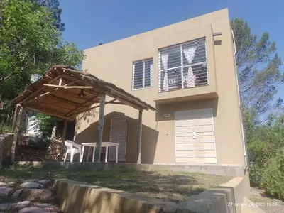 a house with a porch and a building at Cuesta Blanca dos dormitorios cochera in Cuesta Blanca