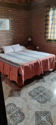 a large bed in a room with a brick wall at Casa Villa Carlos paz in Villa Carlos Paz