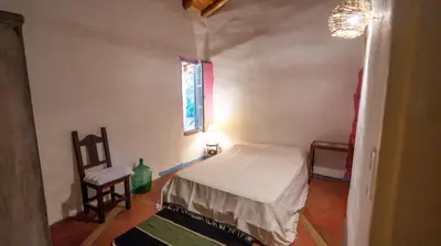 a bedroom with a bed and a chair and a window at Cosmoqui Casa Boutique in Villa de Las Rosas