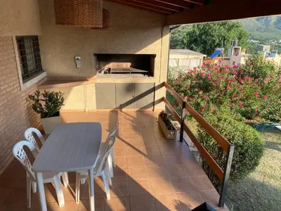 a table and chairs on a patio with a pizza oven at Casa con vista a las Sierras y pileta privada in San Antonio de Arredondo
