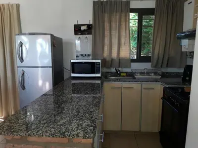 a kitchen with a white refrigerator and a microwave at Casa con vista a las Sierras y pileta privada in San Antonio de Arredondo