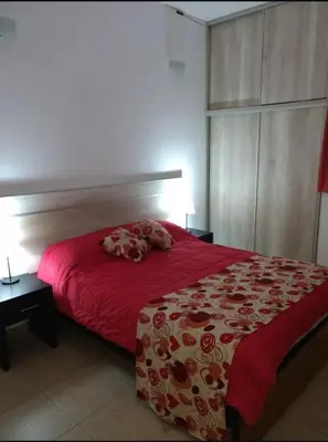 a bedroom with a red bed with a red comforter at Casa con vista a las Sierras y pileta privada in San Antonio de Arredondo