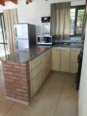 a kitchen with a counter with a microwave and a refrigerator at Casa con vista a las Sierras y pileta privada in San Antonio de Arredondo