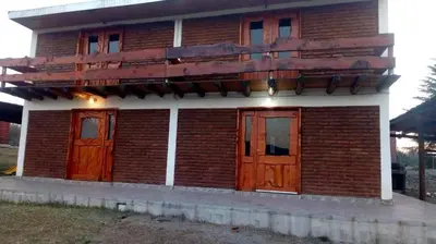 a red brick house with wooden doors and windows at La Fortaleza in Bialet Massé
