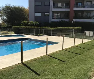 a fence around a swimming pool in front of a building at Departamento - Complejo Casonas de Manantiales in Cordoba