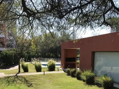 a red building with a garage in a yard at Departamento - Complejo Casonas de Manantiales in Cordoba