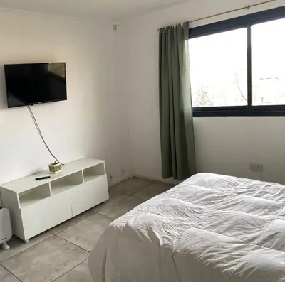 a white bedroom with a bed and a tv at Casa de categoría in Santa Rosa de Calamuchita