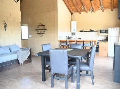 a dining room with a table and chairs and a kitchen at En Las Sierras - Departamento de Montaña in Villa Yacanto