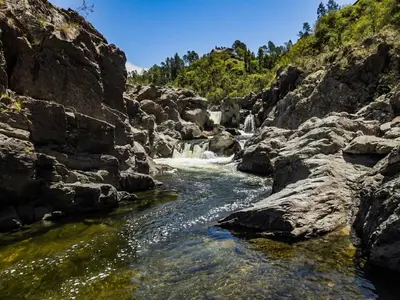 a river with rocks and waterfalls in a canyon at En Las Sierras - Departamento de Montaña in Villa Yacanto