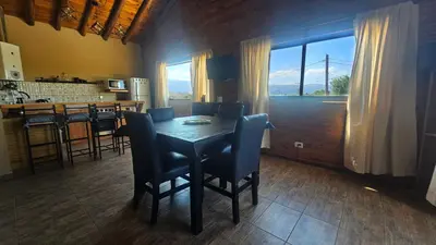 a dining room with a table and chairs and a kitchen at En Las Sierras - Departamento de Montaña in Villa Yacanto