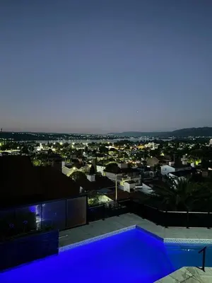 a blue swimming pool on top of a building with a city at Casa minimalista con vistas a las sierras in Villa Carlos Paz