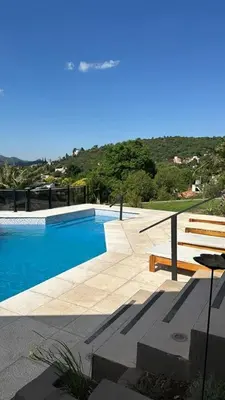 a swimming pool with a wooden bench next to at Casa minimalista con vistas a las sierras in Villa Carlos Paz
