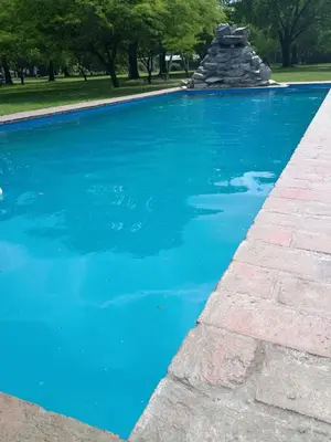 a swimming pool with blue water and a rock fountain at El Parador in Las Bajadas