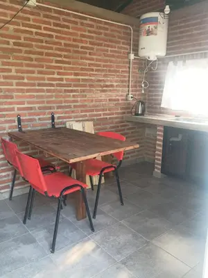 a wooden table with red chairs and a brick wall at El Parador in Las Bajadas