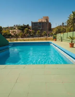 a swimming pool with blue water in a city at KIN Hotel in Villa Carlos Paz